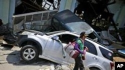 Une femme passe devant l'épave d'une voiture après le tremblement de terre de vendredi dans le quartier de Balaroa à Palu, dans le centre de Sulawesi, en Indonésie, le 2 octobre 2018.