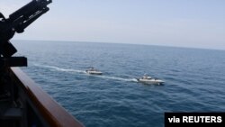Dos buques de la Armada de la Guardia Revolucionaria Islámica Iraní navegan cerca del destructor de misiles USS Paul Hamilton en el Golfo Pérsico el 15 de abril de 2020. Foto provista por la Armada de EE.UU. 