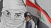 An Iraqi protester carrying his national flag walks past graffiti during ongoing anti-government protests, at Tahrir square in the capital Baghdad.