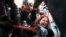 Police try to cut the cuffs off a woman who had handcuffed herself to a fence during a rally supporting Khabarovsk region's governor, Sergei Furgal, in St. Petersburg, Russia, Aug. 1, 2020. Crowds rallied in Khabarovsk as well for a yet another weekend.