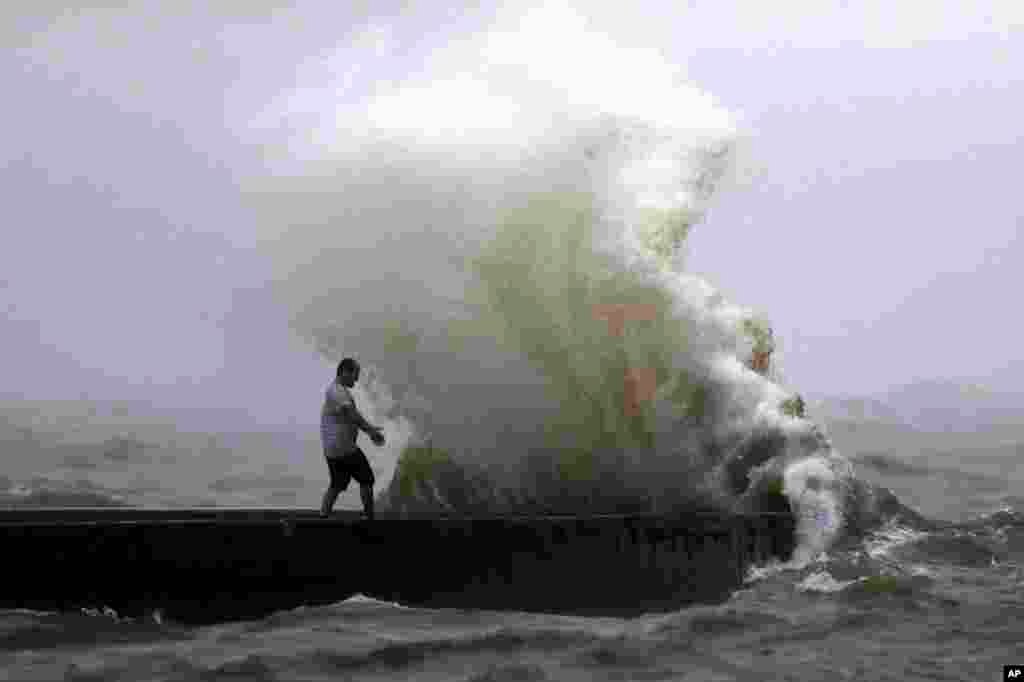 A wave crashes as a man stands on a jetty near Orleans Harbor in Lake Pontchartrain in New Orleans, June 7, 2020, as Tropical Storm Cristobal approaches the Louisiana Coast.