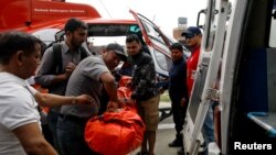 Para petugas membawa seorang korban dari pesawat kecil milik maskapai penerbangan Summit Air yang menabrak helicopter yang terparkir di Bandara Lukla, sebelum membawa korban ke sebuah rumah sakit di Kathmandu, Nepal, 14 April 2019.
