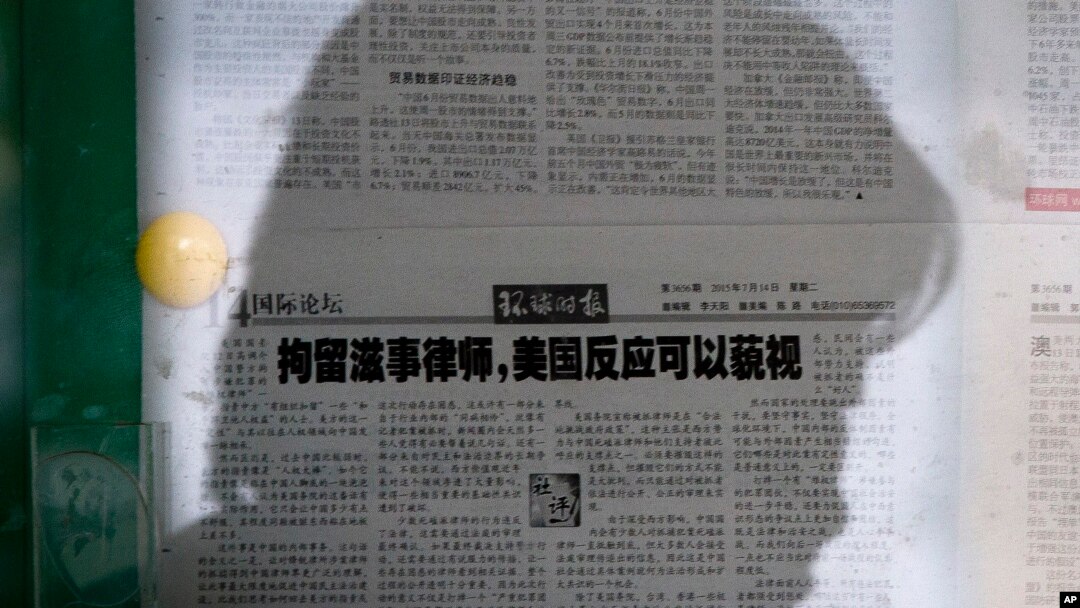资料照片:一名女子在北京的某处报纸橱窗阅读《环球时报》。该报的文章呼吁忽视美国对中国打压维权律师的批评。(2015年7月14日)