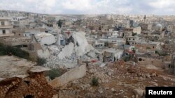 FILE - People inspect a site hit by what residents said were airstrikes carried out by the Russian air force in the town of Darat Izza in the province of Aleppo, Oct. 7, 2015. 