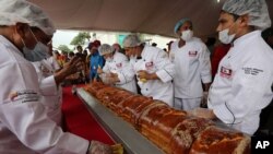 Para koki menyelesaikan Pan de Jamón terbesar di dunia di Caracas, Venezuela, Sabtu, 15 November 2014. Ratusan koki dan penonton membuat Pan de Jamón, makanan khusus Natal, dan juga hallaca terbesar di dunia, tamale versi Venezuela yang dimakan di bulan Desember. (AP Photo/Ariana Cubillos)