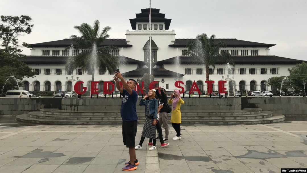 Sejumlah warga berfoto di plasa di depan Gedung Sate yang baru dibuka 31 Desember 2019. Renovasi taman depan dan belakang menelan anggaran total 14,9 miliar APBD Jabar. (Foto:VOA/Rio Tuasikal)