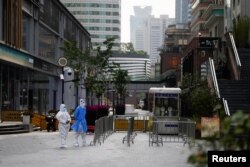 Pekerja dengan pakaian pelindung, berdiri di jalan selama penguncian, di tengah pandemi COVID-19, di Shanghai, China, 2 Mei 2022. (Foto: REUTERS/Aly Song)