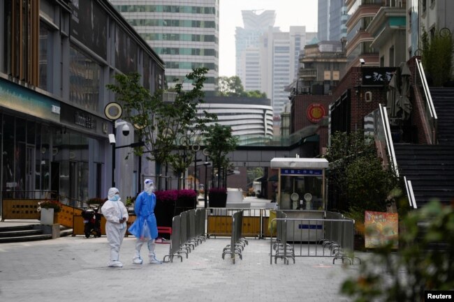Pekerja dengan pakaian pelindung, berdiri di jalan selama penguncian, di tengah pandemi COVID-19, di Shanghai, China, 2 Mei 2022. (Foto: REUTERS/Aly Song)