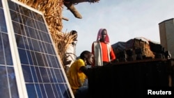 FILE - A youth charges batteries with solar panels at a makeshift shop in a camp for internally displaced persons at a United Nations base in South Sudan, June 17, 2014. 