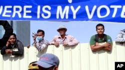  Cambodian workers look through a partition of a construction site below a banner which reads "Where is my vote" as supporters of opposition Cambodia National Rescue Party gather in Phnom Penh, Cambodia, Saturday, Sept. 7, 2013.