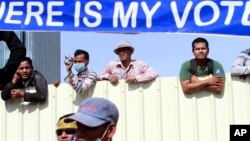 Cambodian workers look through a partition of a construction site below a banner which reads "Where is my vote" as supporters of opposition Cambodia National Rescue Party gather in Phnom Penh, Cambodia, Saturday, Sept. 7, 2013. Nearly 20,000 opposition supporters gathered Saturday in Cambodia's capital to cheer their leaders' demands for an investigation into alleged election irregularities, just a day before the victory of Prime Minister Hun Sen's ruling party is to be ratified. (AP Photo/Heng Sinith)