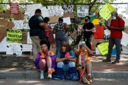 Tia Farrell, left, Tangee Massey, and Shalonda Harris, all of Richmond, Va., wear clothes designed and crocheted by Massey, as people visit the site of protests, June 9, 2020, near the White House in Washington.
