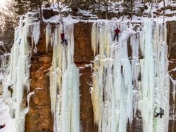 Para peserta tengah unjuk keahlian mereka mendaki bukit es dalam Festival Panjat Es Sandstone di Taman Es Robinson, Sandstone, Minnesota, 8 Januari 2022. (Kerem Yucel / AFP/ilustrasi)