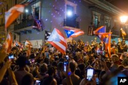 FILE - People celebrate outside the governor's mansion La Fortaleza, after Gov. Ricardo Rossello announced that he is resigning Aug. 2 after nearly two weeks of protests and political upheaval, in San Juan, Puerto Rico, July 25, 2019.