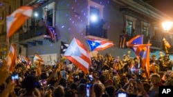 FILE - People celebrate outside the governor's mansion La Fortaleza, after Gov. Ricardo Rossello announced that he is resigning Aug. 2 after nearly two weeks of protests and political upheaval, in San Juan, Puerto Rico, July 25, 2019.
