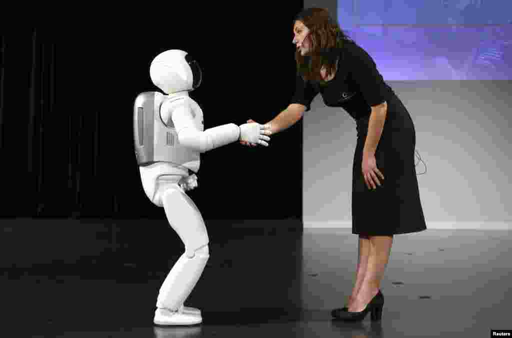 A última versão da Honda do robot humanóide Asimo cumprimenta uma senhora durante uma apresentação em Zaventem junto a Bruxelas na Bélgica. A Honda lançou uma versão actualizada do seu humanóide Asimo que tem agora melhoradas a inteligência e a destreza de mãos e consegue correr a uma velocidade de 9km/hr.