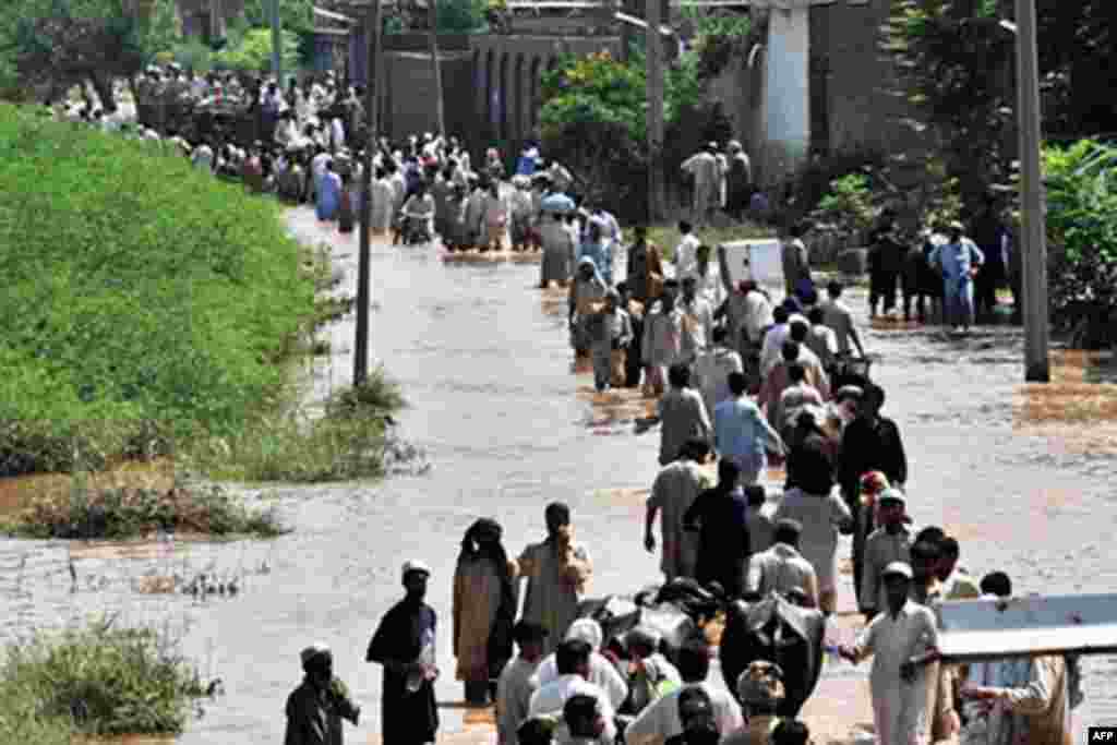 Evacuating residents carry their belongings through floodwaters the Mohib Bhanda area in Nowshera district on July 31, 2010. Rescue workers and troops in northwest Pakistan struggled on July 31 to reach thousands of people affected by the country's worst 