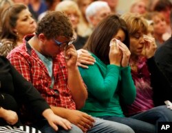 From left, Mathew Downing, Lacey Scroggins and Lisa Scroggins wipe their eyes during service at the New Beginnings Church of God, in Roseburg, Ore., Oct. 4, 2015. Downing and Lacey Scroggins are survivors of a mass shooting at Umpqua Community College.