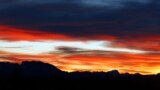 The tower of the Allerheiligen church in Reitham and the mountains of the lake Tegernsee area are silhouetted against the dusk sky in Warngau, Germany.
