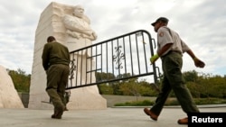 Dos empleados gubernamentales retiran una barrera con la que se había cerrado el monumento a Martin Luther King jr.