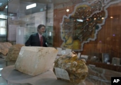 FILE - An Afghan journalist walks by precious stones on display as he attends a news conference held by the Afghan minister of mines in Kabul, June 17, 2010. A 2010 U.S. study estimated that there are more than $1 trillion worth of untapped mineral deposits in the country.