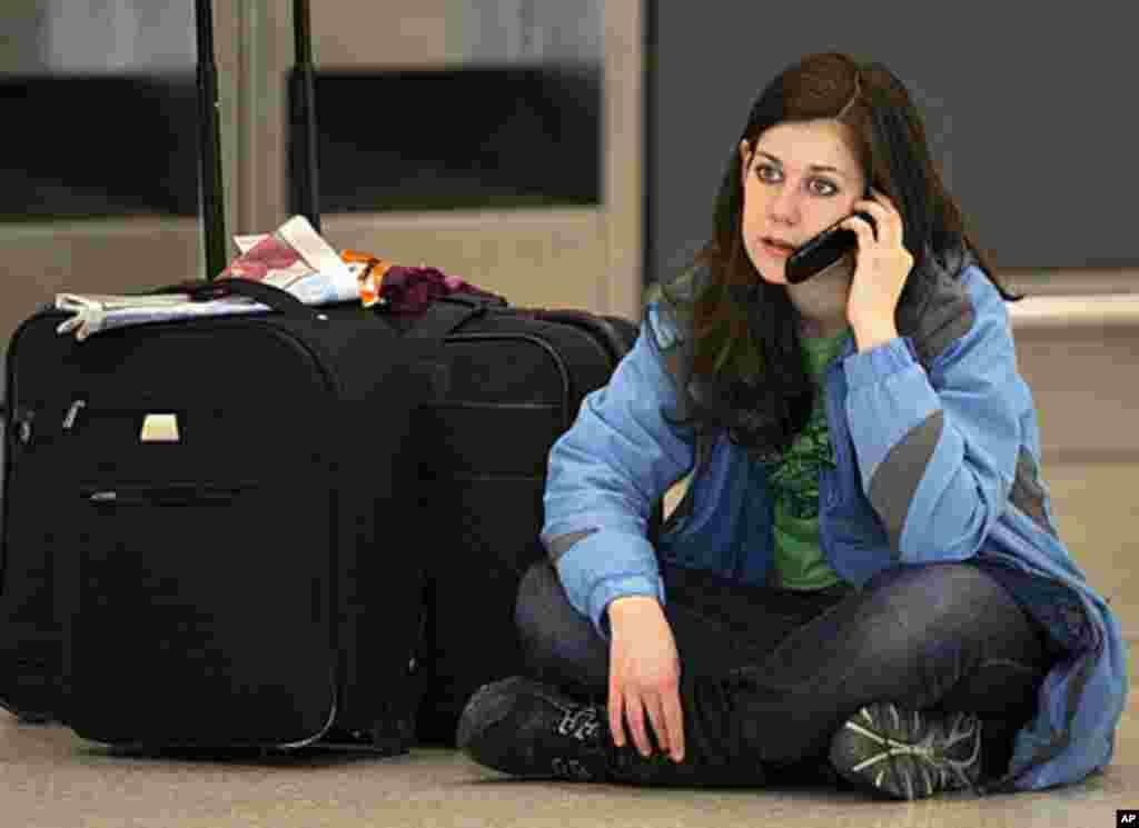 A passenger sits on the floor and talks on her mobile phone after flights were canceled at Edinburgh Airport in Edinburgh, Scotland, May 24, 2011.