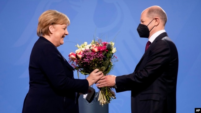 New elected German Chancellor Olaf Scholz, right, gives flowers to former Chancellor Angela Merkel during a handover ceremony in the chancellery in Berlin, Wednesday, Dec. 8, 2021. (Photo/Markus Schreiber)