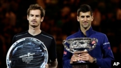 Novak Djokovic, right, of Serbia holds his trophy after defeating Andy Murray, left, of Britain in the men's singles final at the Australian Open tennis championships in Melbourne, Jan. 31, 2016.