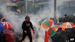 Manifestantes se enfrentan al gas lacrimógeno que les lanzó la policía en Hong Kong, el domingo 29 de septiembre de 2019.