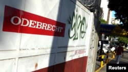 FILE - A man walks past the corporate logo of Odebrecht in a construction site in Caracas, Venezuela, Jan. 26, 2017. 