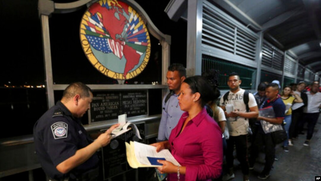 Seorang petugas Dinas Kepabeanan dan Perlindungan Perbatasan memeriksa dokumen para imigran yang mengajukan permohonan suaka di Amerika Serikat, di Jembatan Internasional saat berangkat dari Nuevo Laredo, Meksiko, 17 September 2019. (Foto: AP)