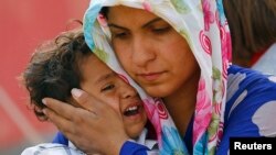 A Syrian Kurdish refugee woman and her child wait after crossing the Turkish-Syrian border near the southeastern town of Suruc in Sanliurfa province, Sept. 27, 2014.