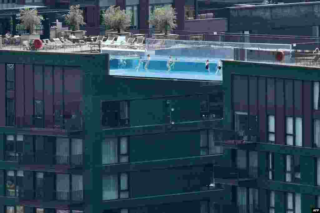 People swim in the Sky Pool - a transparent acrylic swimming pool bridge between two apartment blocks - at Embassy Gardens in southwest London.