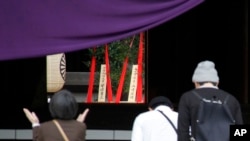 2015年4月21日，人们在一年一度的春季节日参拜位于东京的靖国神社，可以看到背景中心位置是首相安倍晋三供奉的祭品。安倍周二向供奉了已被判刑的二战首领的靖国神社送去宗教祭品，这可能是他不会在出访亚洲和美国前参拜这座有争议的神社的信号。