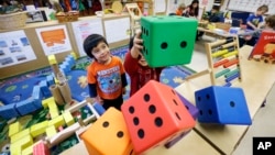 FILE - Children play with large blocks at the Creative Kids Learning Center in Seattle, Feb. 12, 2016. A lack of child care keeps many women out of work, according to the World Economic Forum. 