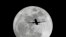 FILE - A commercial airliner crosses the first full Moon of the year, called the Wolf Moon over Whittier on its way to Los Angeles Airport, Jan. 4, 2015.
