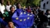 Un migrant portant un drapeau de l'Union européenne assis par terre avec d'autres après avoir pris d'assaut une clôture pour entrer dans l'enclave espagnole de Ceuta, Espagne, 17 février 2017.