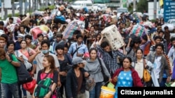 FILE-Cambodian migrant workers carry their belongings as they walk to cross the border at Aranyaprathet in Sa Kaew June 15, 2014. REUTERS/Athit Perawongmetha