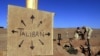 FILE - U.S. Marines fill sandbags on the frontlines of a U.S. Marine Corps base, near a cardboard sign reminding everyone that Taliban forces could be anywhere, in southern Afghanistan, Dec. 1, 2001.