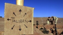 FILE - U.S. Marines fill sandbags on the frontlines of a U.S. Marine Corps base, near a cardboard sign reminding everyone that Taliban forces could be anywhere, in southern Afghanistan, Dec. 1, 2001.