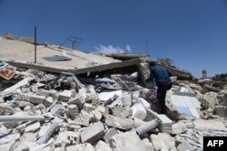 FILE - A man looks through the rubble of a destroyed house in the village of Iblin in the Jabal al-Zawiya region in Syria's rebel-held northwestern Idlib province, June 10, 2021, following reported bombardment by government forces.