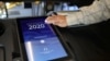 A poll worker sanitizes a voting screen at a polling station on Super Tuesday, March 3, 2020 in Los Angeles, California