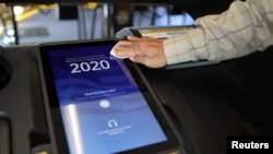 A poll worker sanitizes a voting screen at a polling station on Super Tuesday, March 3, 2020 in Los Angeles, California