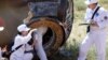 Retrieval team members collect a sample from the charred return capsule of the Shenzhou-9 spacecraft in a remote area of northern China, June 29, 2012.