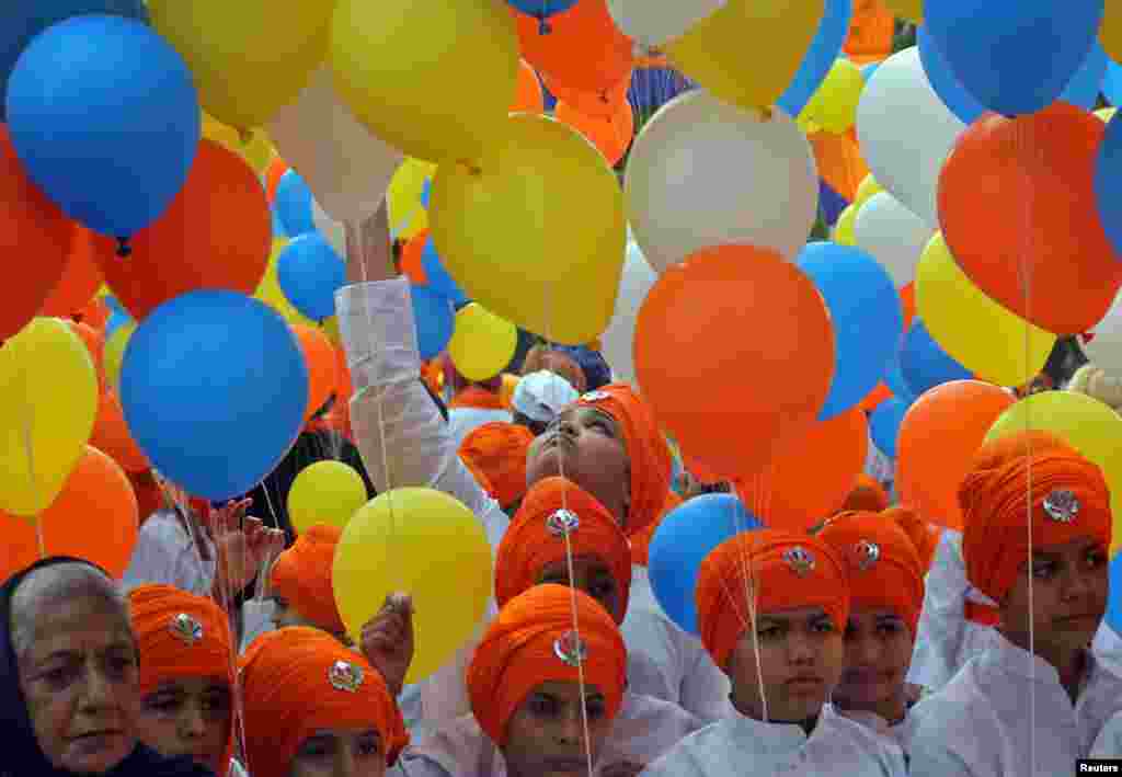 School children hold balloons as they take part in a religious procession to mark the 550th birth anniversary of Guru Nanak Dev, the first Sikh Guru and founder of Sikh faith, in Chandigarh, India.