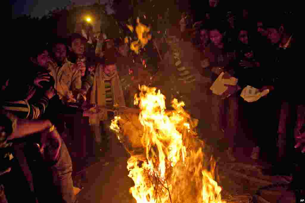 2012年12月30日在印度新德里举行的一个悼念被轮奸的女子的烛光守夜中，印度抗议者焚烧强奸者的肖像。