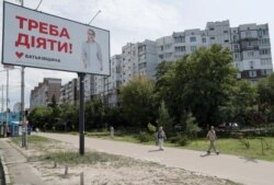 People walk past an election campaign poster with a portrait of Batkivshchyna party leader Yulia Tymoshenko ahead of the upcoming parliamentary election in Kiev, Ukraine, July 18, 2019.