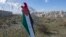 Protesters post a placard with the colors of the Palestinian flags and Arabic that reads "Jerusalem is the eternal capital of Palestine," at a barbed wire surrounding the Israeli separation wall and an Israeli settlement near Ramallah, Jan. 31, 2020.