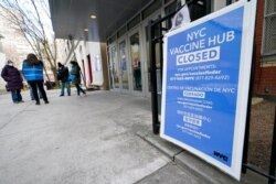 FILE - People who had appointments to get COVID-19 vaccinations talk to New York City health care workers outside a closed vaccine hub in the Brooklyn borough of New York, Jan. 21, 2021.