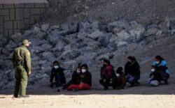 FILE - Migrants are detained by a U.S. Border Patrol agent as they turn themselves in to request asylum, after crossing into El Paso, Texas, as seen from Ciudad Juarez, Mexico, Feb. 9, 2021.